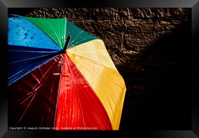 Open umbrella against the intense sun with bright colors and dar Framed Print by Joaquin Corbalan