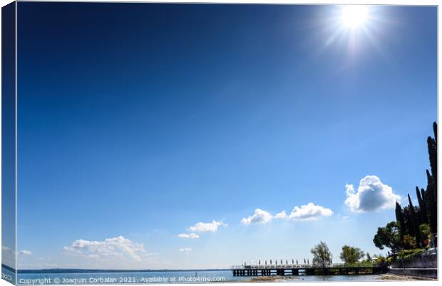 A strong sun illuminates the lake on a clear summer day, with sp Canvas Print by Joaquin Corbalan