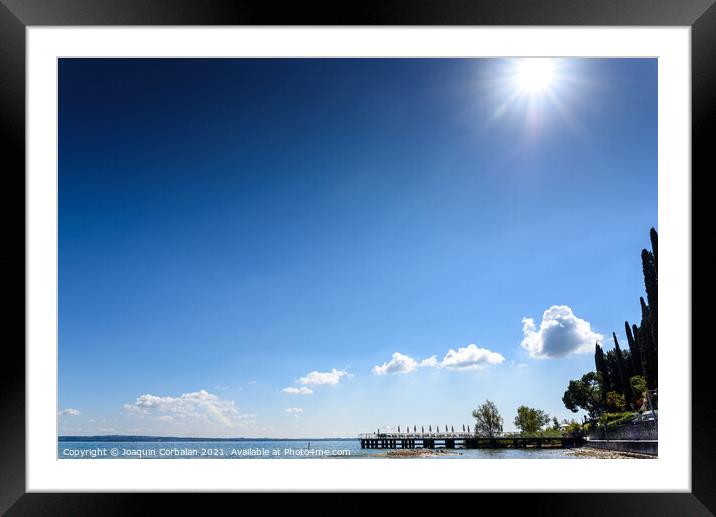 A strong sun illuminates the lake on a clear summer day, with sp Framed Mounted Print by Joaquin Corbalan