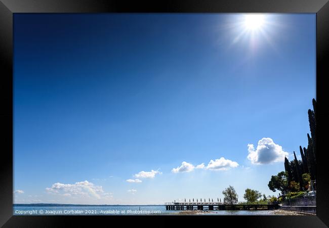 A strong sun illuminates the lake on a clear summer day, with sp Framed Print by Joaquin Corbalan