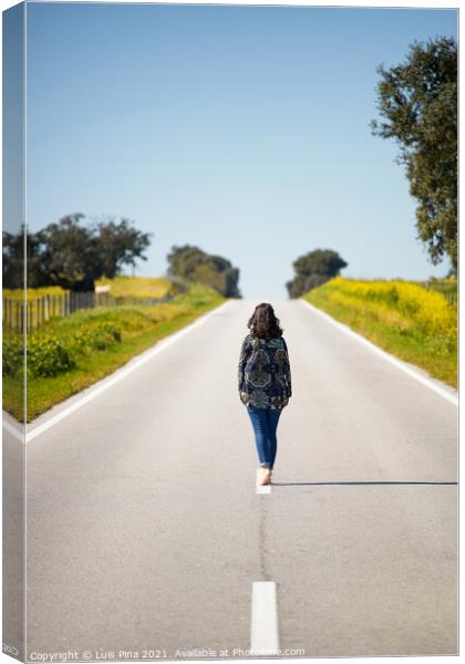 Woman walking on the middle of a road in beautiful yellow flowers landscape in Alentejo, Portugal Canvas Print by Luis Pina
