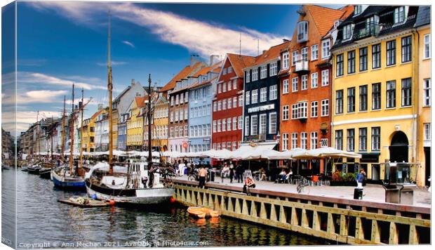Nyhavn Copenhagen colourful houses with cafes and people alongside canal with boats. Canvas Print by Ann Mechan