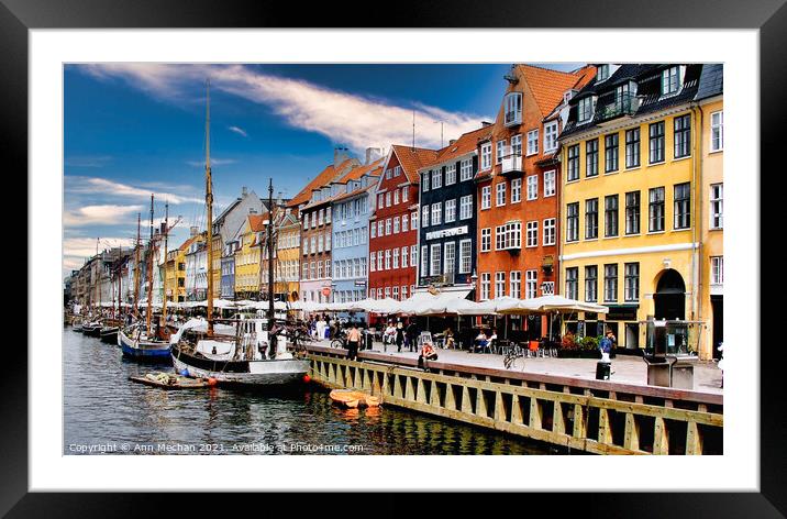 Nyhavn Copenhagen colourful houses with cafes and people alongside canal with boats. Framed Mounted Print by Ann Mechan