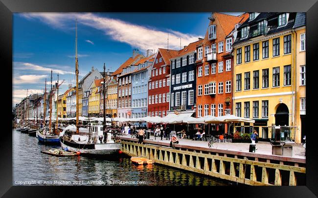Nyhavn Copenhagen colourful houses with cafes and people alongside canal with boats. Framed Print by Ann Mechan