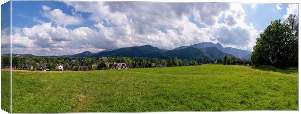 Panoramic view of green grass meadow countryside field with A shaped houses against sleeping knight tatra mountain aka as giewont and dramatic clouds located in Zakopane, South Poland, Europe Canvas Print by Arpan Bhatia