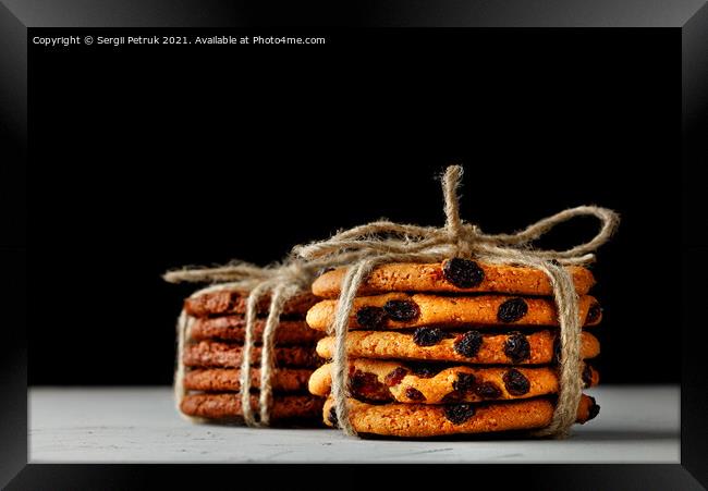 Stacks of homemade oatmeal and chocolate biscuits tied with a rope lie on a gray concrete surface against a black background. Close-up, copy space. Framed Print by Sergii Petruk