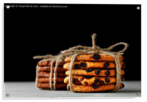 Stacks of homemade oatmeal and chocolate biscuits tied with a rope lie on a gray concrete surface against a black background. Close-up, copy space. Acrylic by Sergii Petruk