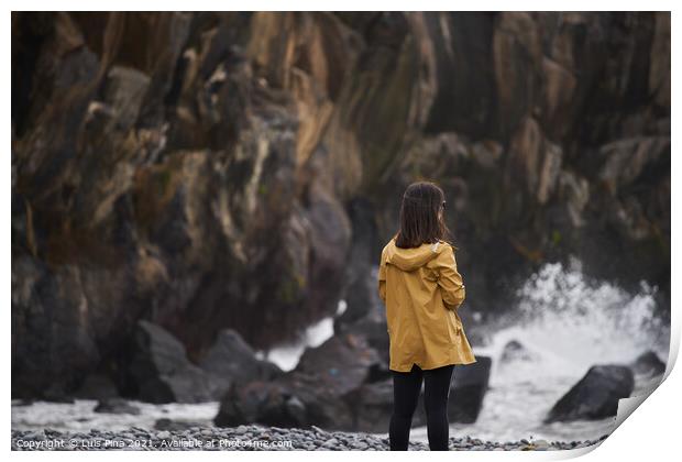 Woman on a yellow rain jacket looking to the sea with rocks on the background, in Madeira Print by Luis Pina