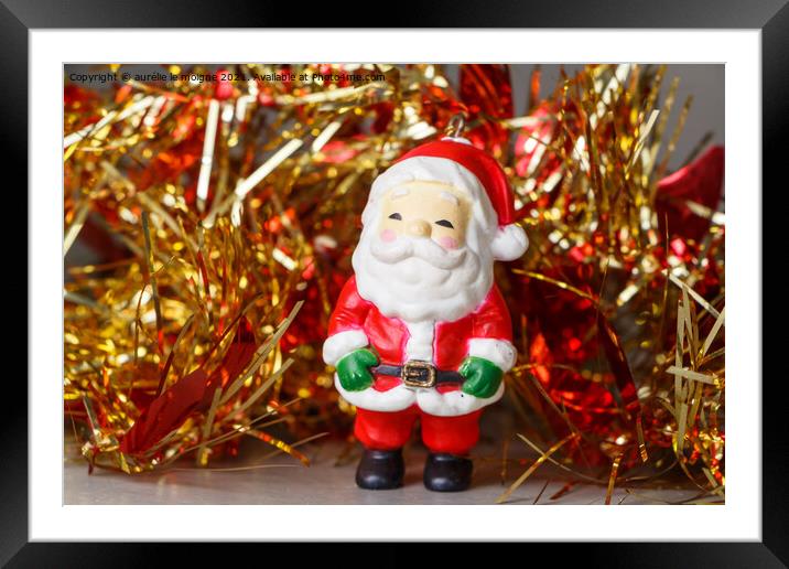 Santa Claus figurine and red and golden tinsel Framed Mounted Print by aurélie le moigne