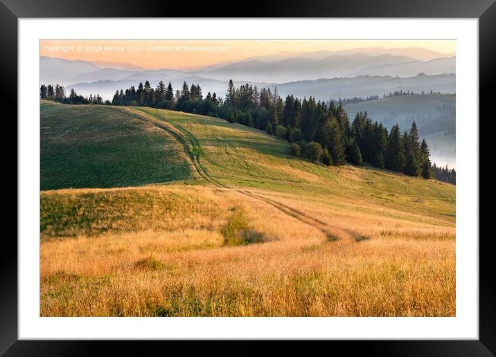 Morning landscapes of the mountainous Carpathians, sunrise illuminates the rural road that runs along the ridge of the hill. Framed Mounted Print by Sergii Petruk