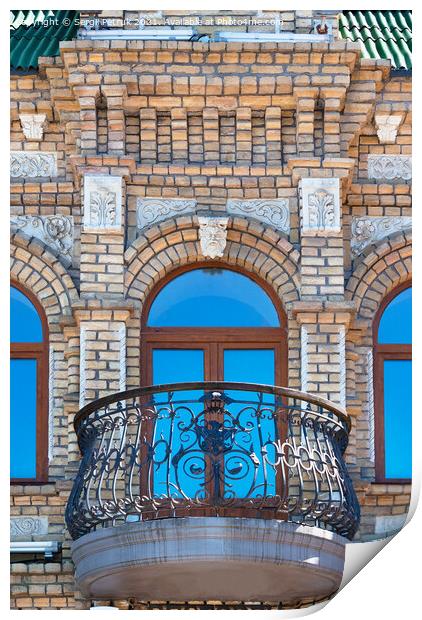 Arched windows with a beautiful, expressive balcony on the brick facade of the old house and the reflection of the blue sky in the glass windows. Print by Sergii Petruk