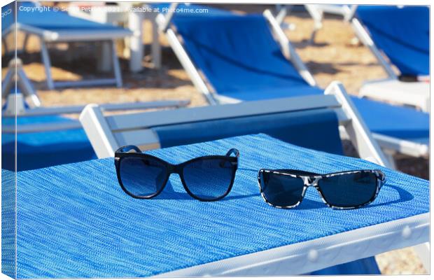 A pair of sunglasses lie on a blue sun lounger under the sun on a summer day. Canvas Print by Sergii Petruk