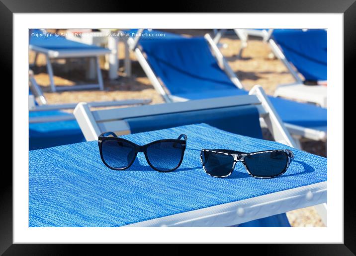 A pair of sunglasses lie on a blue sun lounger under the sun on a summer day. Framed Mounted Print by Sergii Petruk