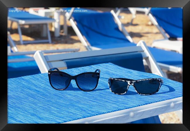 A pair of sunglasses lie on a blue sun lounger under the sun on a summer day. Framed Print by Sergii Petruk