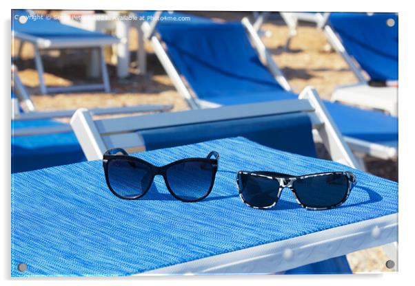 A pair of sunglasses lie on a blue sun lounger under the sun on a summer day. Acrylic by Sergii Petruk