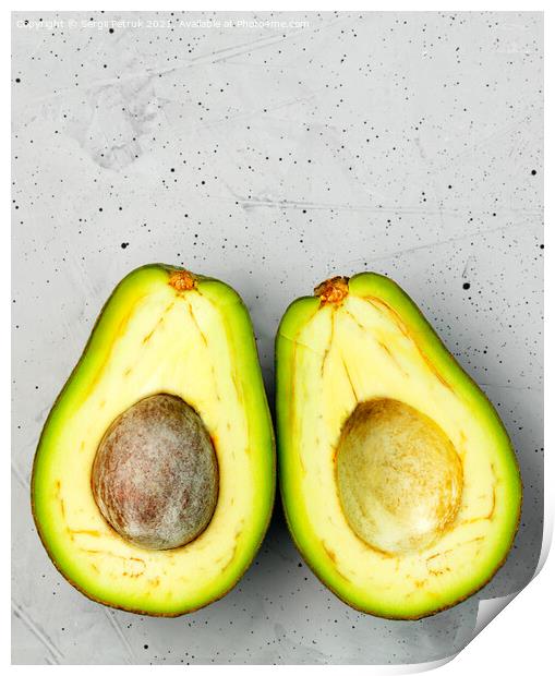 Avocado, cut in half, one slice with a core, on a gray concrete background, top view. Print by Sergii Petruk
