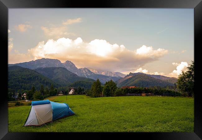 Camping tent put up on green grass meadow field against tatra mountains landscape during sunset sunrise and dramatic clouds, adventure in wild nature concept. Framed Print by Arpan Bhatia