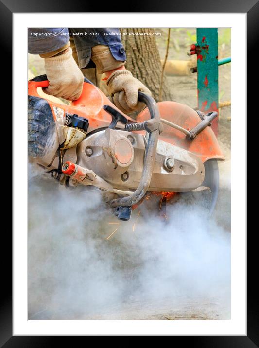 A builder uses a portable cutter to cut a concrete structure in a cloud of dust. Framed Mounted Print by Sergii Petruk