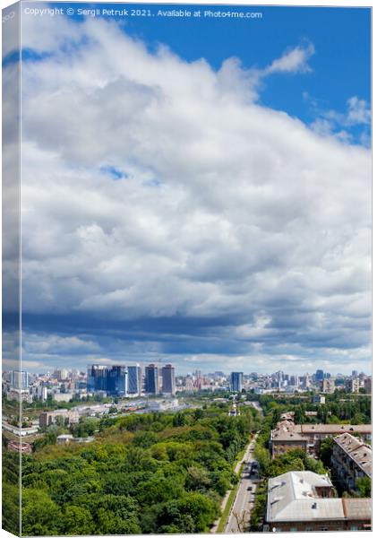 A large white and gray cloud loomed over a green park in the old residential area of the city and new buildings on the horizon against the backdrop of a bright summer day. Canvas Print by Sergii Petruk
