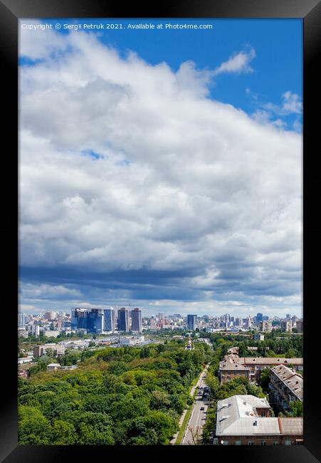 A large white and gray cloud loomed over a green park in the old residential area of the city and new buildings on the horizon against the backdrop of a bright summer day. Framed Print by Sergii Petruk