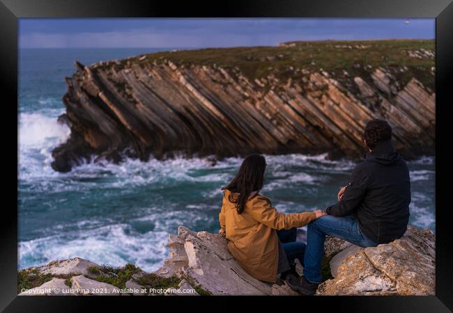 Couple caucasian female and male holding hands looking at cliff landscape with ocean waves in Baleal Island, Peniche, Portugal Framed Print by Luis Pina