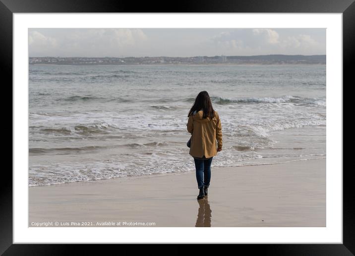 Woman walking on a beach with a yellow jacket in Peniche, Portugal Framed Mounted Print by Luis Pina