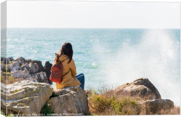 Caucasian traveler woman looking at the waves on the sea with a yellow jacket in Peniche, Portugal Canvas Print by Luis Pina