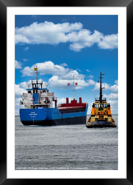Coastal freighter escorted by tugboat Framed Mounted Print by Roger Mechan
