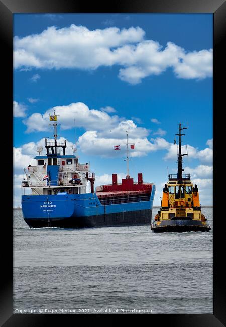 Coastal freighter escorted by tugboat Framed Print by Roger Mechan
