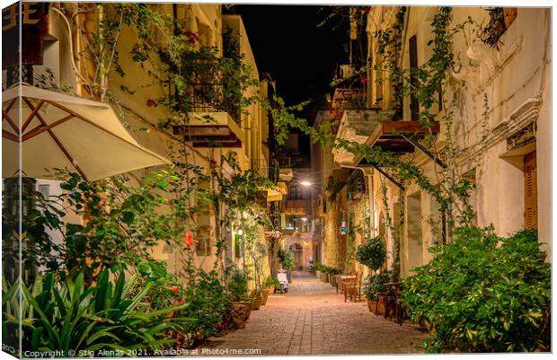 an illuminated alley with green plants and balconies on the side Canvas Print by Stig Alenäs