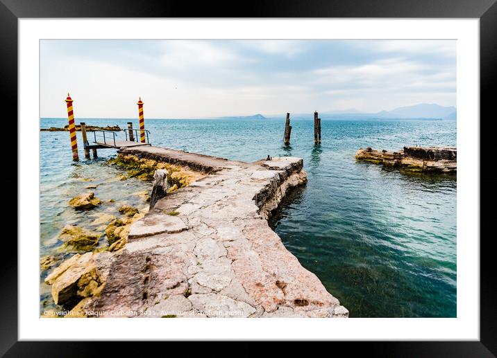 Old stone jetty at the tip of San Vigilio, on Lago di Garda with colorful mooring poles on Framed Mounted Print by Joaquin Corbalan