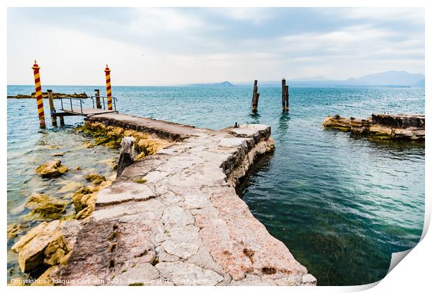 Old stone jetty at the tip of San Vigilio, on Lago di Garda with colorful mooring poles on Print by Joaquin Corbalan