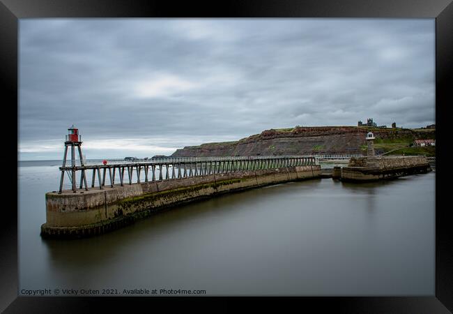 Whitby Pier with the lighthouse & Whitby Abbey in the distance.  Framed Print by Vicky Outen