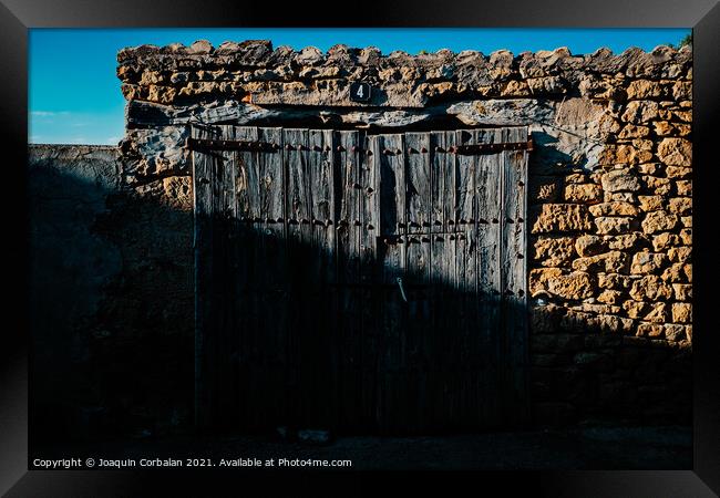 Old and decrepit wooden gate, half lit by the sun, in an unpopul Framed Print by Joaquin Corbalan