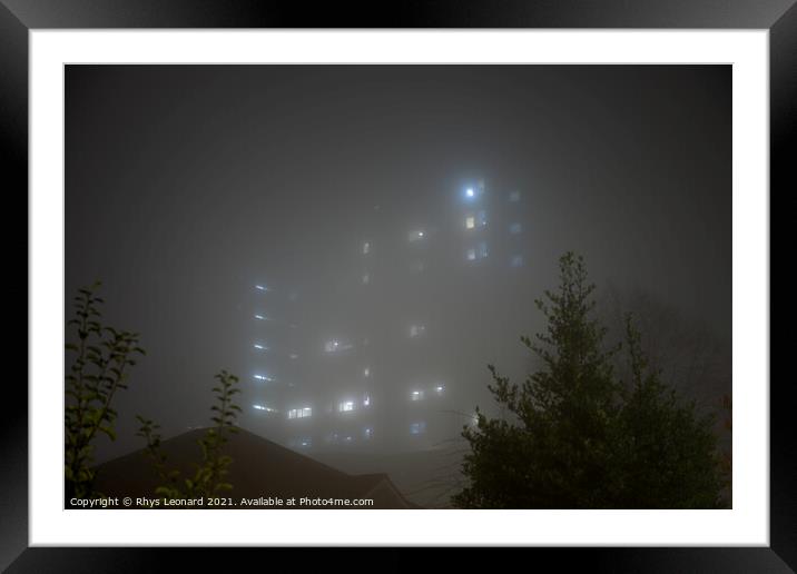 Eerie sky scraper hospital lights shine through very thick fog. Framed Mounted Print by Rhys Leonard
