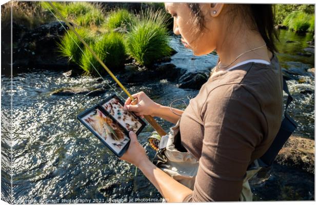 A close up of an asian female selecting fly fishing flies from a box Canvas Print by SnapT Photography