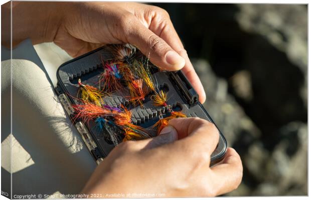 A close up of an asian female selecting salmon fly fishing flies from a box Canvas Print by SnapT Photography
