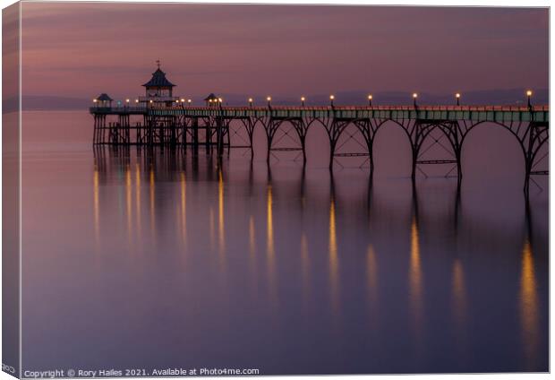 Clevedon Pier with lights reflecting onto a calm sea Canvas Print by Rory Hailes