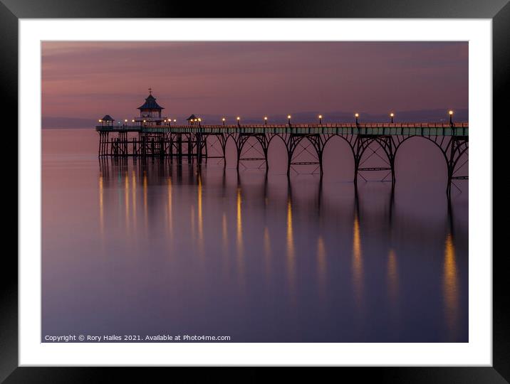 Clevedon Pier with lights reflecting onto a calm sea Framed Mounted Print by Rory Hailes