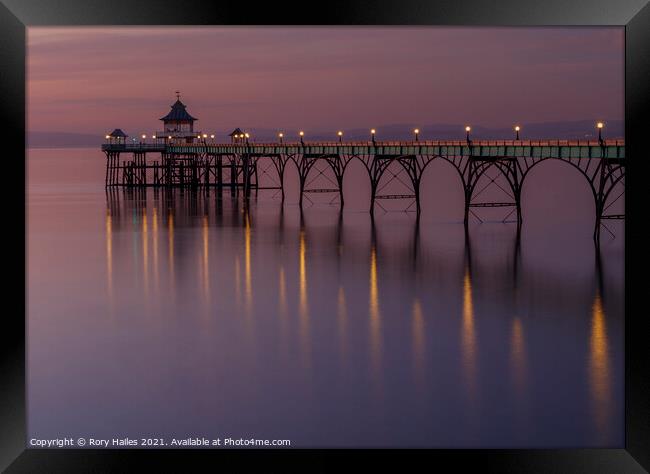 Clevedon Pier with lights reflecting onto a calm sea Framed Print by Rory Hailes