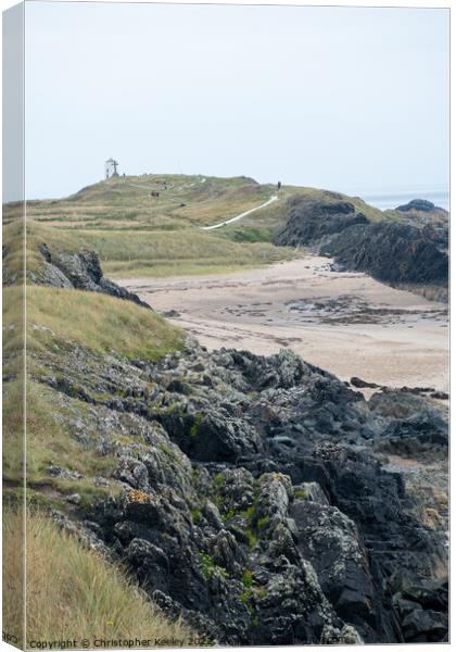 Rocky beach and lighthouse of Ynys Llanddwyn Canvas Print by Christopher Keeley