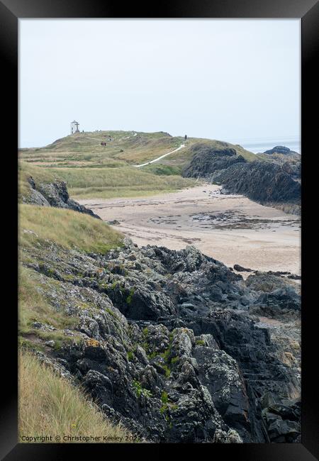 Rocky beach and lighthouse of Ynys Llanddwyn Framed Print by Christopher Keeley