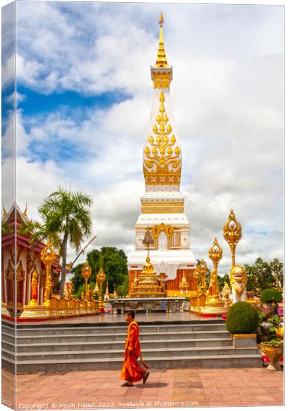 A monml walks past the spire in Wat Phra That Phanom Canvas Print by Kevin Hellon