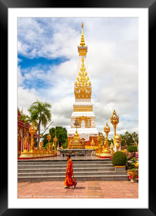 A monml walks past the spire in Wat Phra That Phanom Framed Mounted Print by Kevin Hellon