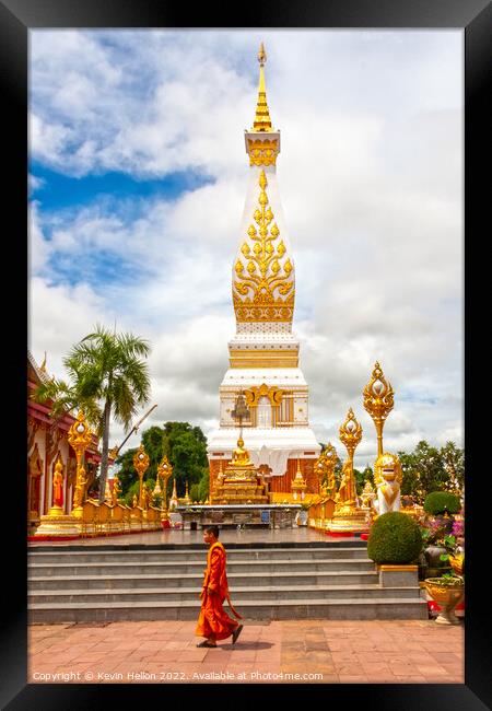 A monml walks past the spire in Wat Phra That Phanom Framed Print by Kevin Hellon