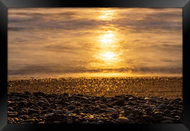Golden sunlight on sea and pebble beach Framed Print by Phil Crean