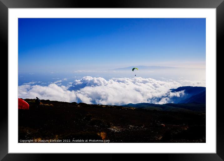 Paragliding above mountain peaks and white clouds during winter  Framed Mounted Print by Joaquin Corbalan