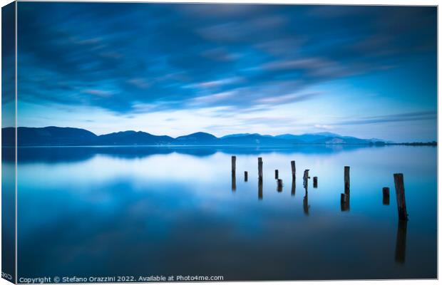 Remains of a wooden jetty in a blue lake Canvas Print by Stefano Orazzini
