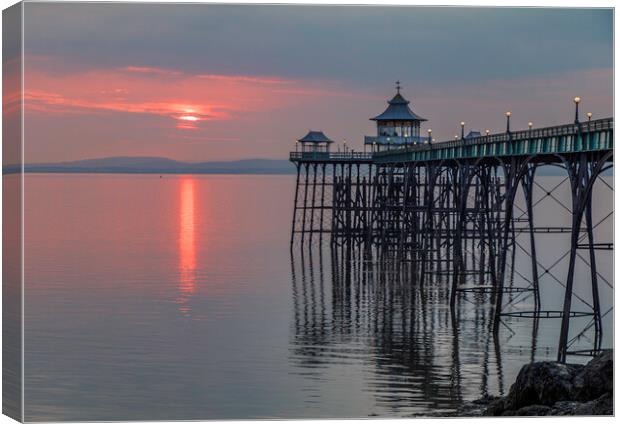 Clevedon Pier at sunset with it legs reflecting in the sea Canvas Print by Rory Hailes