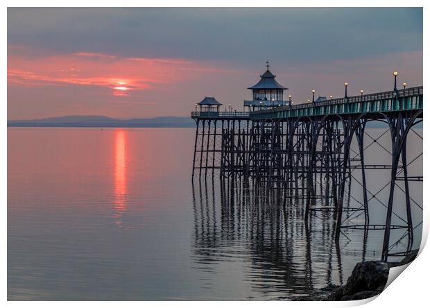 Clevedon Pier at sunset with it legs reflecting in the sea Print by Rory Hailes